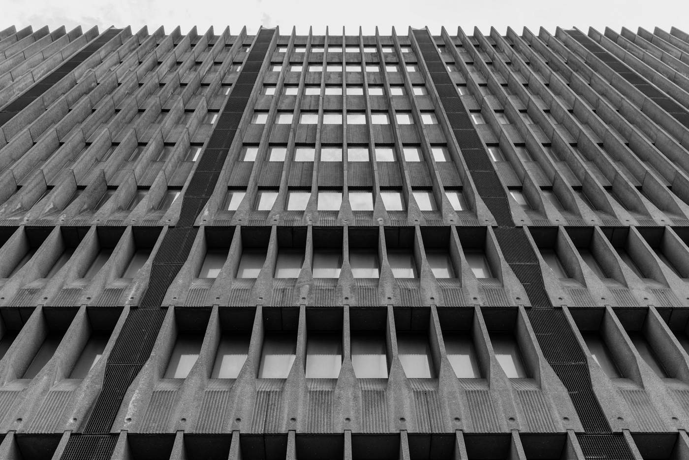 Repeating concrete fins and recessed windows on a building façade.